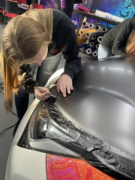 Studente wrapt nauwkeurig rond koplampen — hands-on training